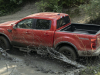 2021-ford-ranger-tremor-lariat-exterior-006-rear-three-quarters-driving-through-mud