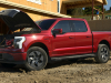 2022-ford-f-150-lightning-lariat-exterior-025-front-three-quarters-construction-site-frunk-open