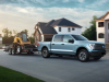 2022-ford-f-150-lightning-pro-exterior-010-front-three-quarters-towing-trailer-with-bobcat
