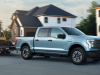 2022-ford-f-150-lightning-pro-exterior-011-front-three-quarters-towing-trailer-with-bobcat