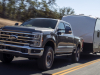 2023-ford-super-duty-f-250-lariat-tremor-off-road-package-press-photos-exterior-013-front-three-quarters-towing-trailer