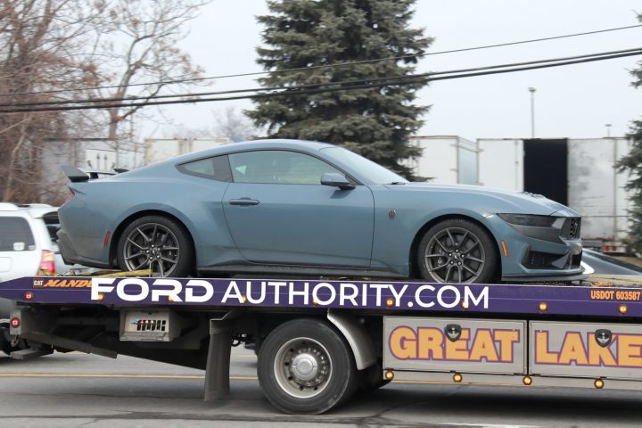 A passenger side view of a 2024 Ford Mustang Dark Horse in Vapor Blue Metallic. The Mustang is on a flatbed trailer. 