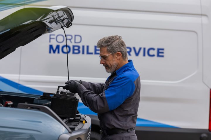 Photo showing a Ford Mobile Pickup And Delivery Service technician working on a vehicle. This perk encourages owners to stick with Ford when buying a new vehicle.