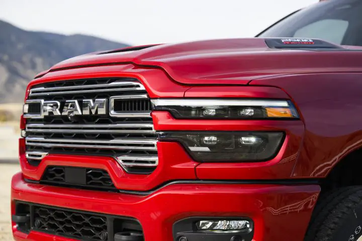 Photo showing the front end of the 2025 Ram 2500 from a front three-quarters angle, focused on the Ram logo on the grille. Ram will make 25 new announcements over the next 18 months.