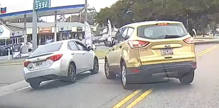 Video still of the 2015 Ford Escape almost hitting the Toyota Corolla, which makes an illegal pass right in front of it. The cars are viewed from behind. 