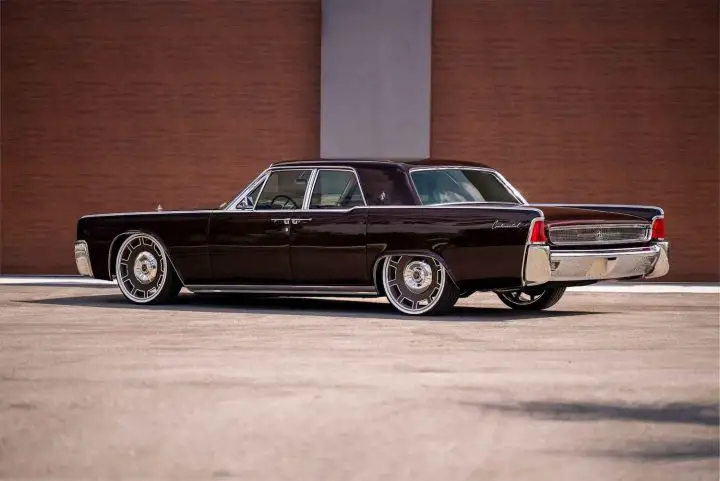 A photo showing the exterior of a Coyote-powered 1962 Lincoln Continental restomod from a rear three quarters angle.