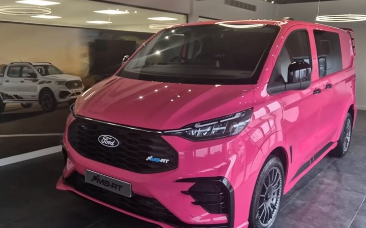 Video still of Tim Burton's new Ford Transit Custom MS-RT van in bright pink, shown from a front three-quarters angle.