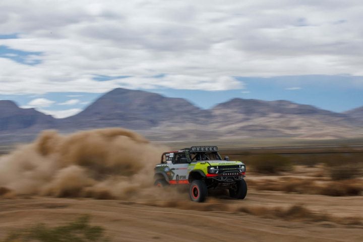 A photo of the Ford Bronco Raptor competing in the 2025 Mint 400, shown from a front three-quarters angle. The new U-Haul Toy Hauler is capable of towing the Bronco and other full-size Ford models.