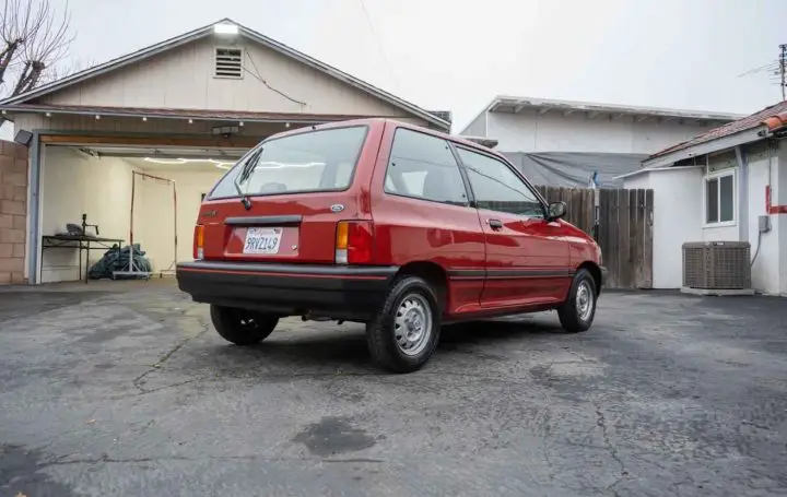 A photo showing the exterior of a 1988 Ford Festiva LX from a rear three quarters angle.