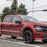 A red 2026 Ford F-150 Lobo, front three quarters view driving on public road.