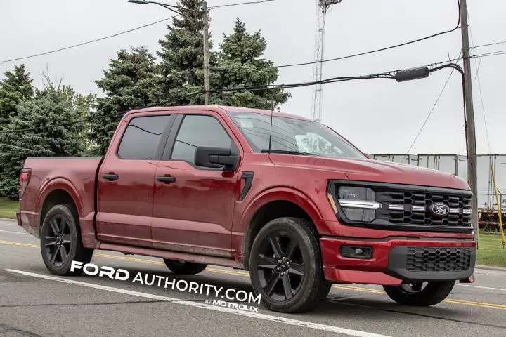 A red 2026 Ford F-150 Lobo, front three quarters view driving on public road. 