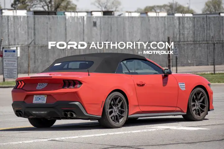 2026 Ford Mustang GT with camo covering the 5.0 and pony badges, pictured from the rear passenger side. 