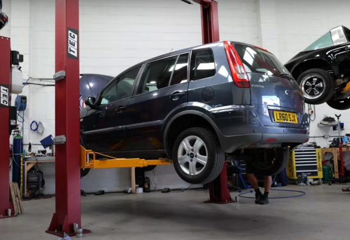 Video still of the Ford Fusion MPV on a lift at the exhaust shop. Jack McNeill borrowed parts from a Fusion ST to turn the Fusion MPV into a fun little machine. 