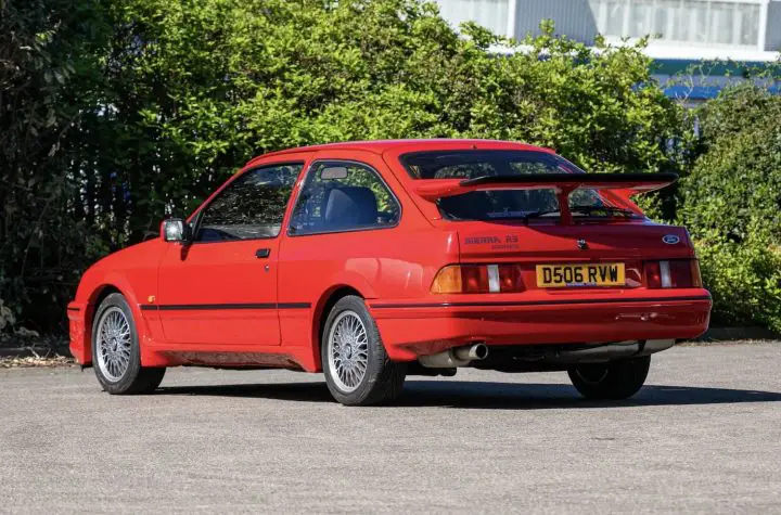 A photo showing the exterior of a Rosso Red Ford Sierra RS Cosworth from a rear three quarters angle.