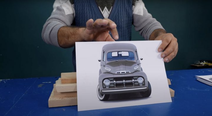 A photo showing a wooden carving of a 1952 Ford panel truck from a front angle.