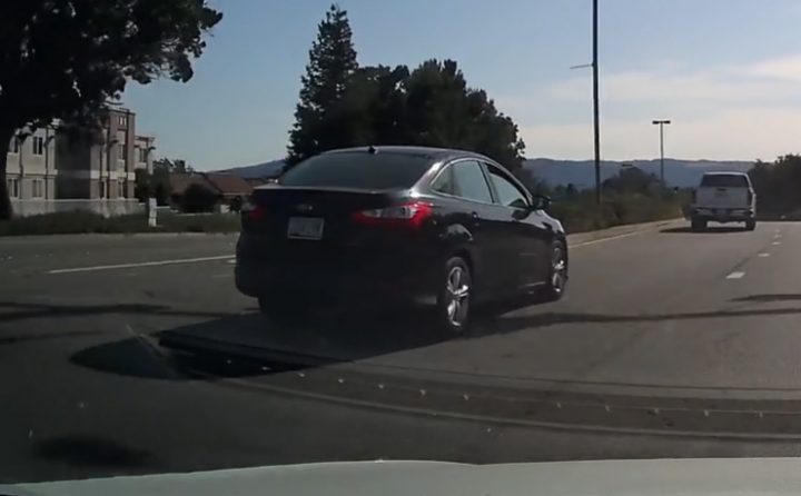 Video still of the Ford Focus riding properly in its lane before it makes a questionable decision to blow by a yellow line. 