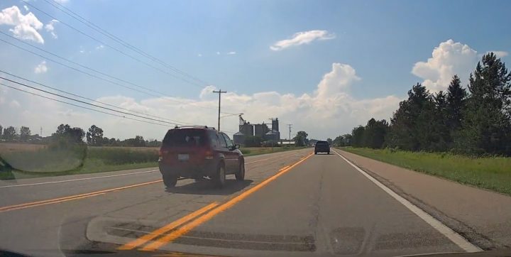 Video still of the Ford Escape using the center lane as an inappropriate passing lane. They would be stopped by the driver of a pickup just ahead of them.