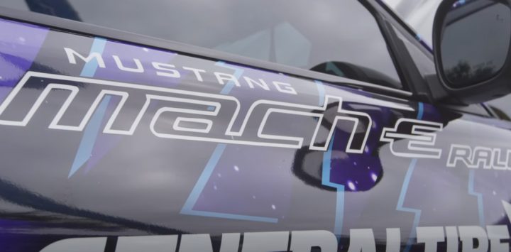 Closeup of the Ford Mustang Mach-E Rally "Livewire" door, showing its graphics and purple wrap. It's the brainchild of off-road driver Jim Beaver.