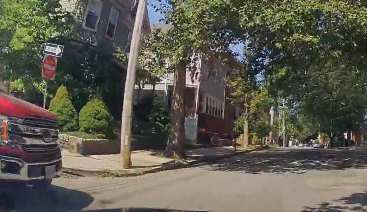 Video still of the dashcam footage showing the driver of a Ford F-150 blowing a stop sign and sideswiping the cammer. The pickup can be seen to the left.