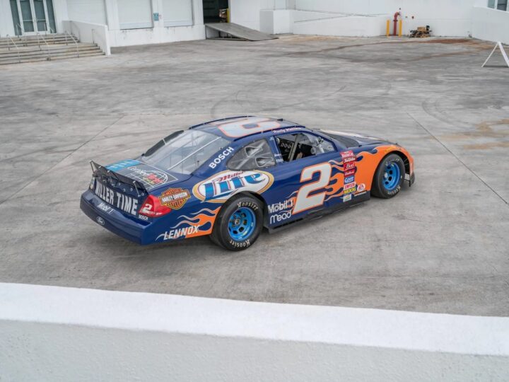 A photo showing the exterior of a Rusty Wallace 2002 Ford Taurus NASCAR racer from a rear three quarters angle.